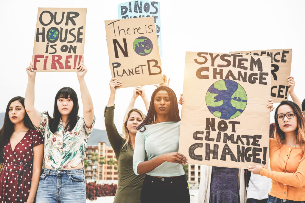 Women from different backgrounds in a climate demonstration standing with signs.