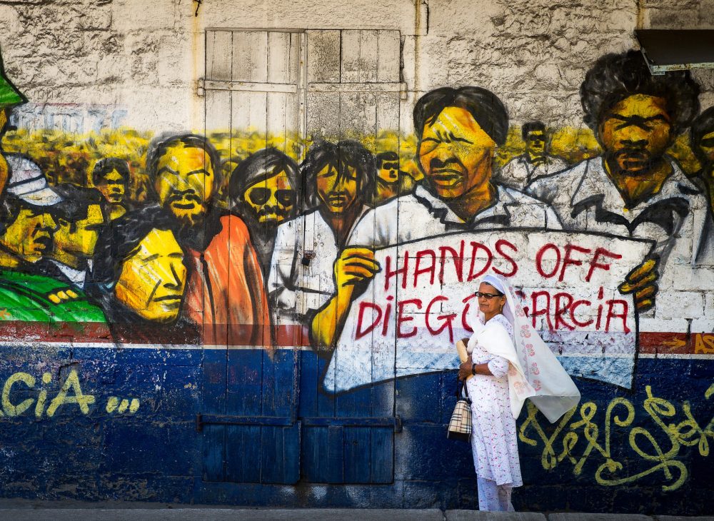 'Hands off Diego Garcia,' a woman stands in front of a painted wall in Ville Noire, Mauritius.
Photo: Dmitry Chulov/Dreamstime